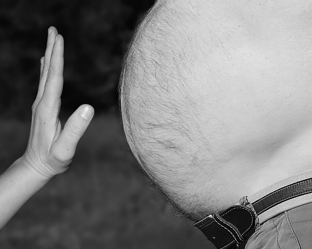 Mužské veľké brucho, pred ktorým je ženská ruka